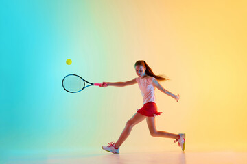 Dynamic portrait of athletic teenage girl perfectly serving ball to opponent in motion in neon light against blue-yellow background. Concept of individual kind of sports, fashion, tournament, action.