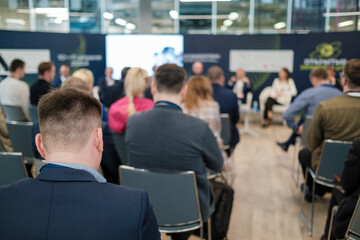 Focused shot of attendees at a business conference. The discussion panel is blurred in the...