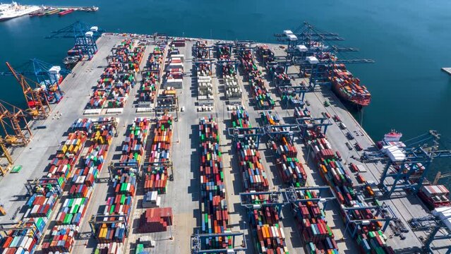 Aerial hyper lapse view of a industrial cargo container terminal with loading and unloading activity