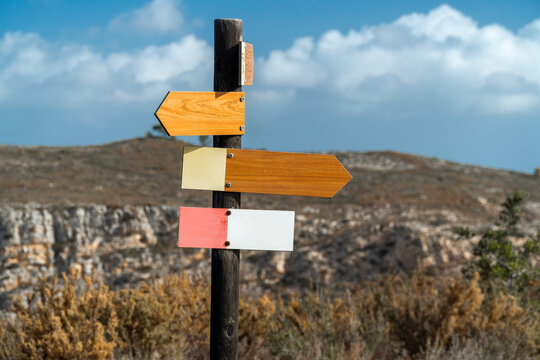 Signpost with wooden arrows, landmark for hiking, indications and directions. Natural background.