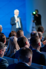 Focused view of a businessman delivering a speech at a corporate conference with an attentive...