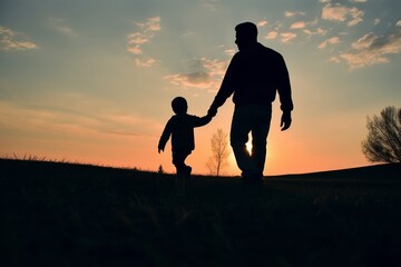 A man and a child are walking together in a field at sunset
