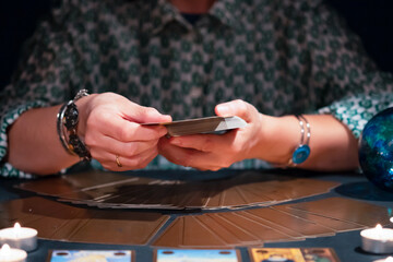 Tarot reader with tarot cards.Tarot cards face down on table near burning candles and crystal ball.