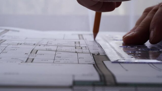 The designer draws with a compass and ruler on the drawing