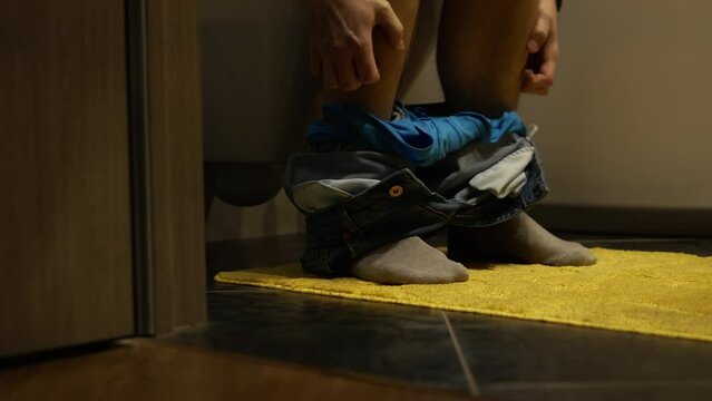 A man is in the toilet, his stomach hurts from food poisoning. Gonorrhea in men, bacterial intestinal infection.