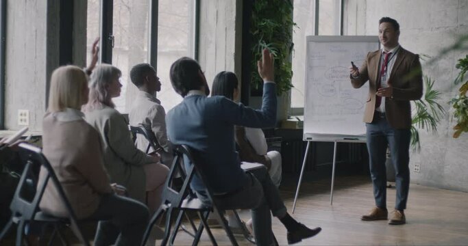 Creative coach giving speech on personal development teaching in business school while men and women listening. Corporate education and ambition concept.