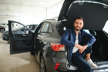 Young man is choosing a new vehicle in car dealership