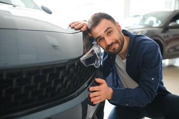 Young man is choosing a new vehicle in car dealership