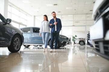 Portrait of a beautiful young couple choosing a new car at a car dealership