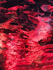 Red abstract background texture of ice crystals on glass with a red light behind it.