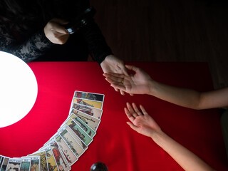 An overhead view of a tarot card reading in progress with a palm reading and cards laid out on a...