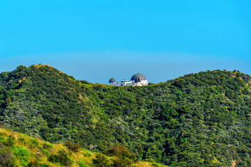 Griffith Observatory Amidst Green Hill against Blue Sky