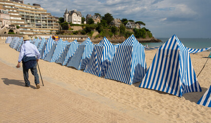 blue and white striped canvas beach tents on the beach of Dinard, Brittany, France