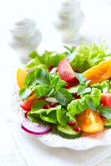 Salad with red and yellow Tomatoes and Pomegranate Seeds on bright wooden Background. Close up.