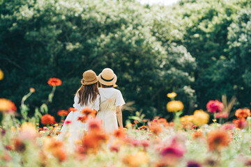 お花畑に麦わら帽子、白いワンピースの女の子二人