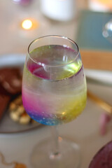 Plate of pastel macarons, cookies and chocolate, cup of tea of coffee, glass of bubble water, various berries, books and accessories on the table. Selective focus, pastel colors.
