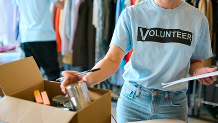 Close Up Of Female Charity Worker Checking Food Donations At Foodbank Or Thrift Store