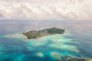 Drone view of green ocean waters. Cumulus clouds over the Fiji Islands. Vacation and travel concept.