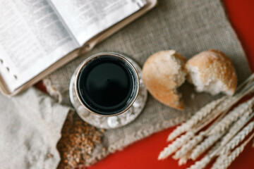 Cup with wine, bread and open Bible, Christian communion