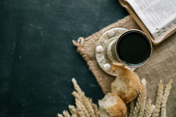 Cup with wine, bread and open Bible, Christian communion