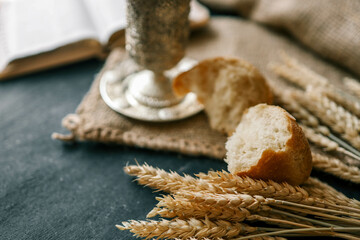 Cup with wine, bread and open Bible, Christian communion