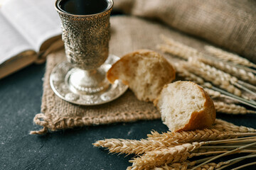 Cup with wine, bread and open Bible, Christian communion