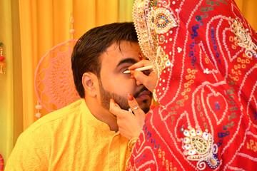 Sister applying kajal in her brother's eyes