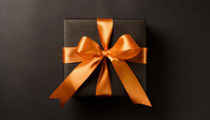 Top view photo of black giftbox with orange satin ribbon bow on isolated black background with copyspace
