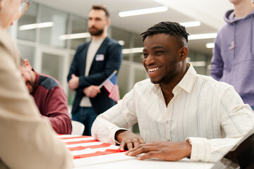 Smiling, attractive African American man talking with polling station worker at registration table