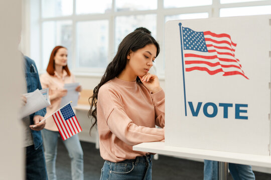 Pensive young woman, Asian voter waiting in line standing in polling booth voting at polling station