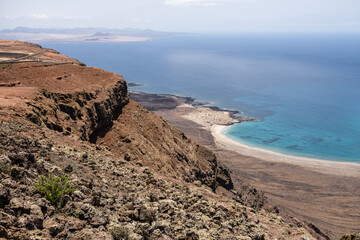 Views of Caleta de Famara from the viewpoint of El Rio. Turquoise ocean. Blue sky with big white clouds. Caleta de Sebo. Village. Volcanoes. Lanzarote, Canary Islands, Spain