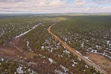 Aerial view of gravel road in cloudy spring weather, Lapland, Finland.