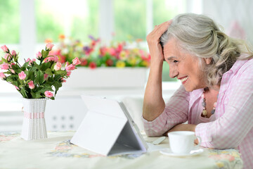 Cute nice senior woman using laptop at home