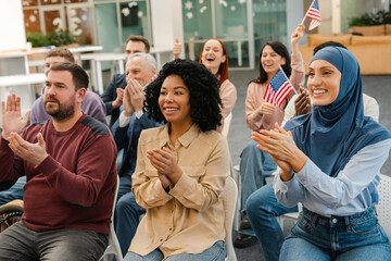 Multiracial people holding American flag, applauding, listening to their candidate, supporting