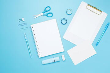 Creative flat lay mockup design of workspace. Top view composition with white notebook, to do list and stationery on blue background