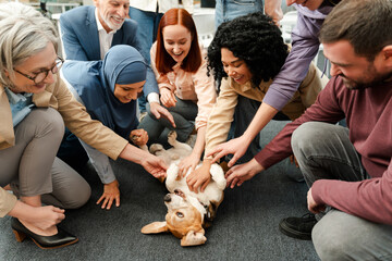 Group of multinational smiling people, business team petting dog together, resting, team building