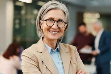 Cheerful smiling mature woman businesswoman CEO wearing eyeglasses and formal wear looking at camera