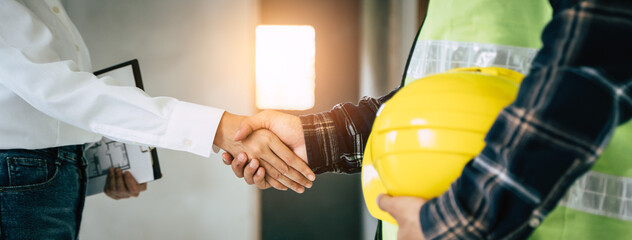 construction worker and contractor. Client shaking hands with team builder in renovation site.