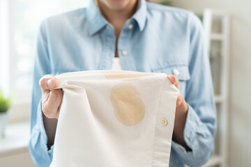 Housewife, asian young woman hand in holding shirt, showing making stain, spot dirty or smudge on...