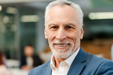 Portrait of smiling handsome senior man, gray-haired, mature businessman looking at camera