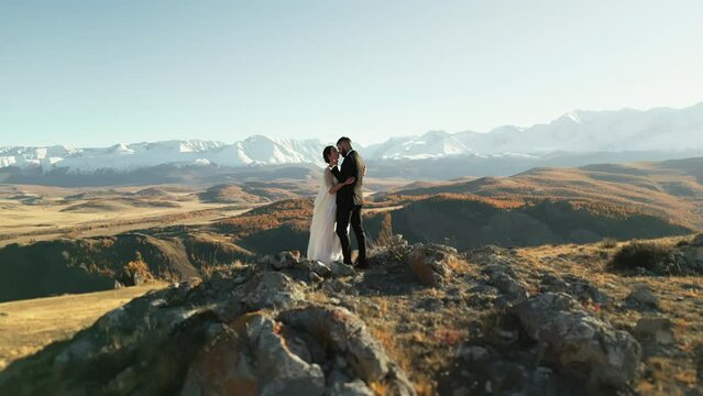 Newlyweds. Married couple in the mountains. A man and a woman in wedding dresses against a background of snow-capped mountains. Wedding couple. A happy family. 