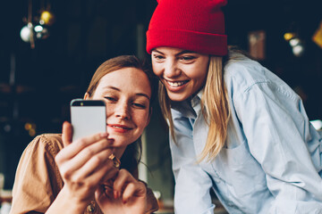 Cheerful two hipsters watching funny videos online on smartphone device connected to 4G...