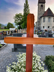 A wooden cross is standing in front of a cemetery