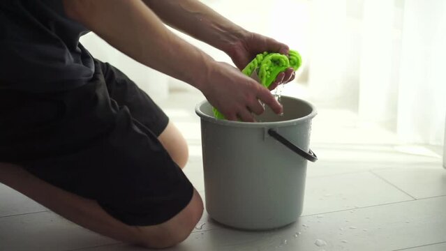 man rinsing floor cloth in bucket
