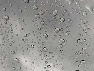Water Rain Droplets Drops on Car Glass Window with Gray Sky Background