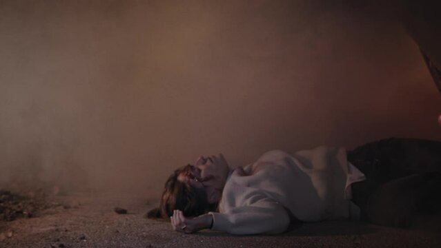 A young woman laying on the ground after a car crash