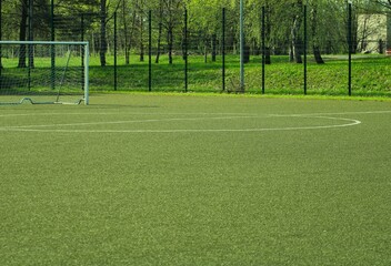 an artificial turf soccer field surrounded by a metal fence with a circle in the middle and a...