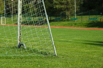 natural grass sports field with a red running track in the background and the corner of a soccer goal in the foreground