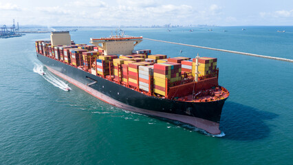 Aerial side view of cargo ship with contrail in the ocean sea ship carrying container and running...