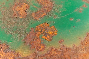 Bright spots of structural rust on the painted bottom of a metal barrel as a background.           ...